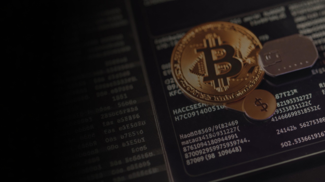 Gold Bitcoin coins rest on a dark surface printed with hexadecimal columns