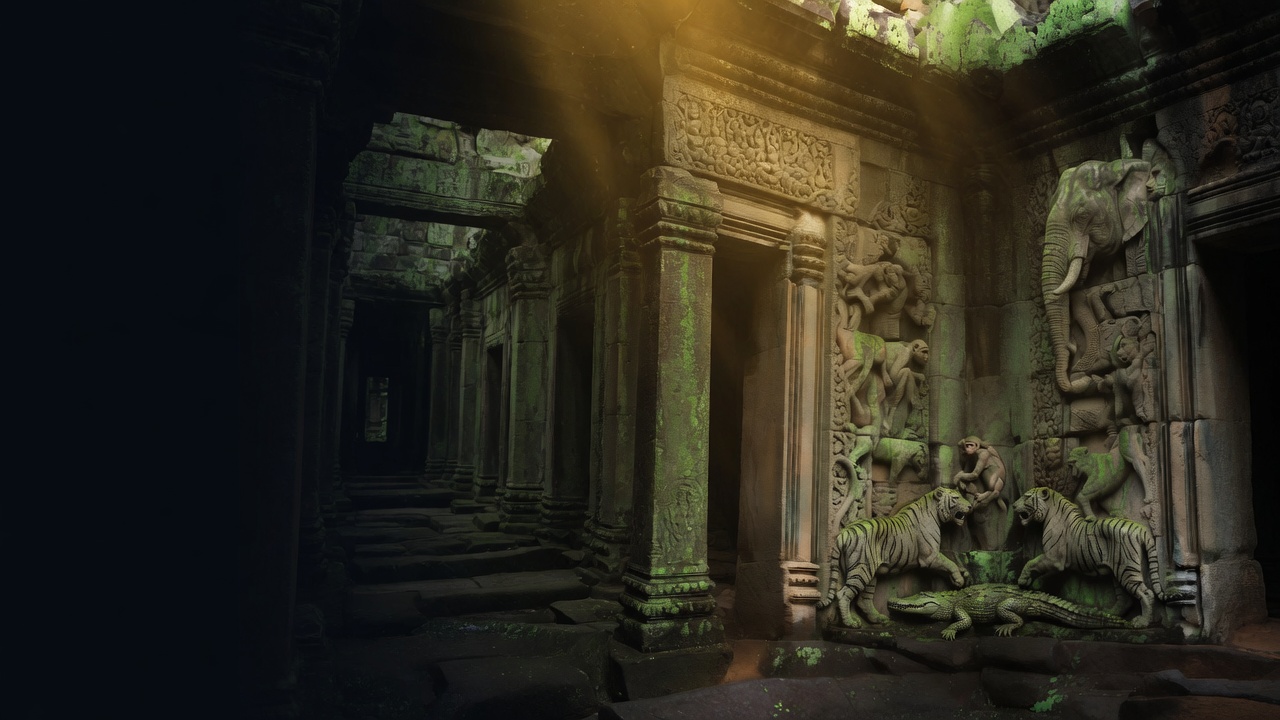 A mossy Khmer temple gallery carved with tigers, a crocodile, monkeys, and an elephant