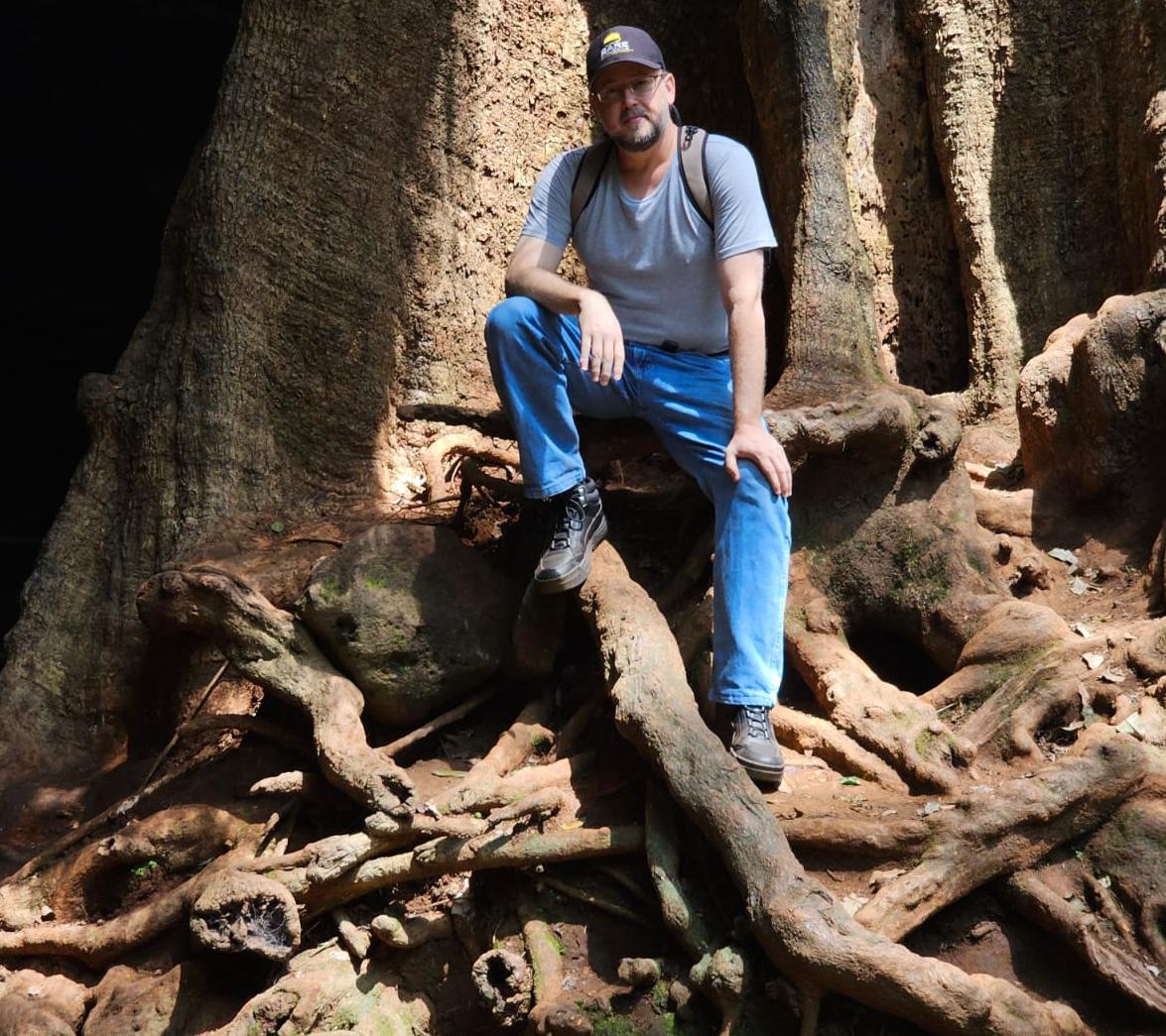 Jeremy sitting on a huge tree root in the Karura Forest, Nairobi